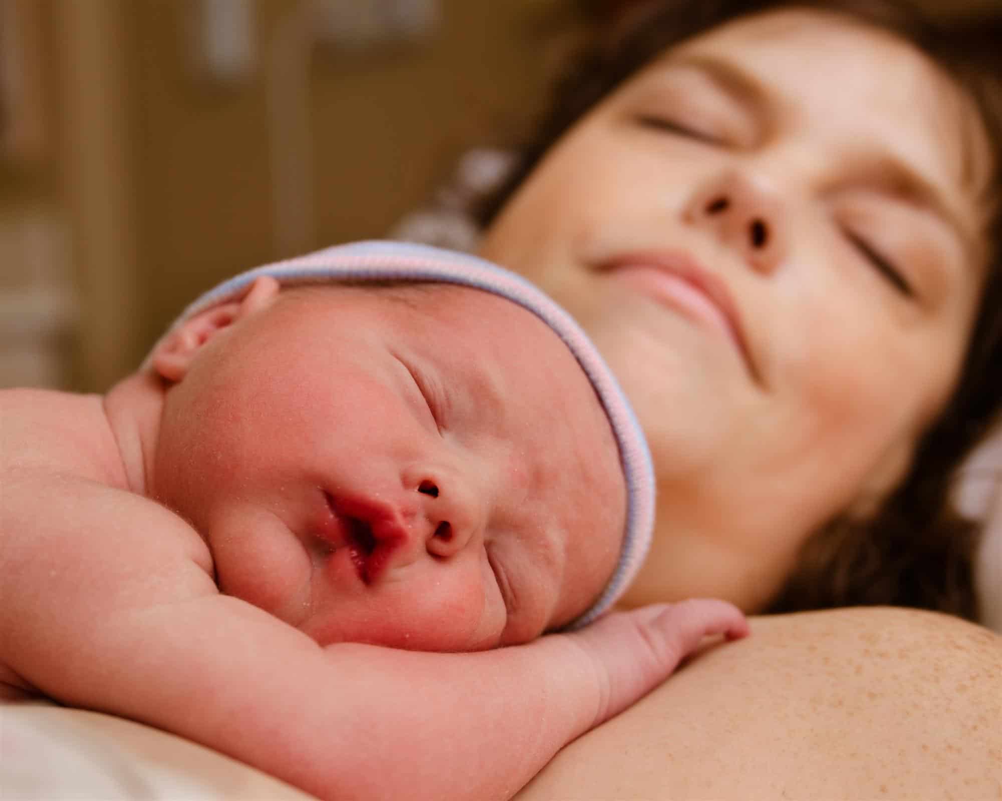 cute newborn baby resting on mothers chest